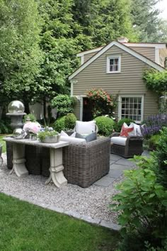 an outdoor patio with wicker furniture and flowers on the table, surrounded by greenery