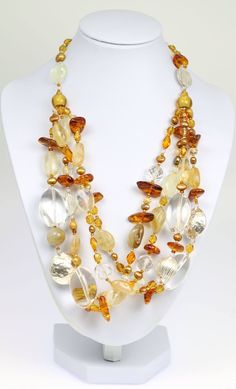 Earth tones come alive in the exquisite design of the Amber Citrine Crystal Quartz Beaded Gemstone Necklace. This luxurious handmade necklace features a multi-strand design that fills out the neckline and complements rounded and plunging styles to perfection. The design combines smooth crystal quartz and orange citrine beads with chunky of golden amber and freshwater pearls that are gold in tone. For a sleek finishing touch, hammered fine silver beads are mixed in, bringing a cool tone to the ot Citrine Crystal Necklace, Citrine Jewelry, Citrine Beads, Citrine Necklace, Beads Bracelet Design, Quartz Crystal Necklace, Unusual Jewelry, Amber Beads, Citrine Crystal