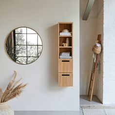 a white room with a mirror and wooden cabinet next to the wall in front of it