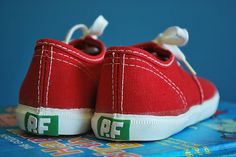 a pair of red tennis shoes sitting on top of a blue book with white laces