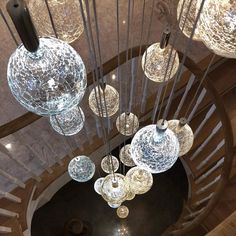 a bunch of glass balls hanging from a spiral stair case in a house or office