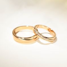 two gold wedding rings with diamonds on them sitting side by side against a white background