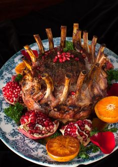 a large piece of meat with pomegranates and orange slices on a plate