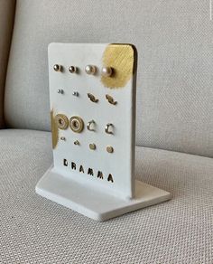 a white and gold display on a gray couch with buttons in the middle, which says drama