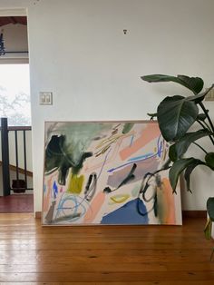 a large painting on the wall next to a potted plant