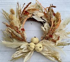 a wreath with dried flowers and leaves on a white wooden surface, ready to be used as a decoration