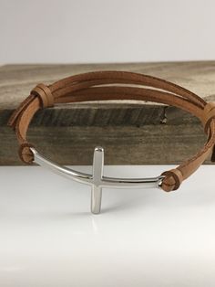 a cross bracelet on top of a wooden block with a metal bar in the middle