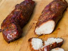 two pieces of meat sitting on top of a wooden cutting board