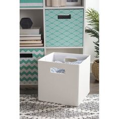 a white storage box sitting on top of a rug in front of a book shelf