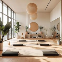 a room with yoga mats, potted plants and large windows