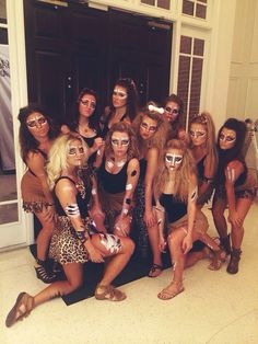 a group of women posing for a photo in front of a door with their faces painted