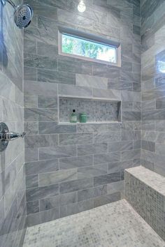 a walk in shower sitting under a window next to a tiled wall and flooring