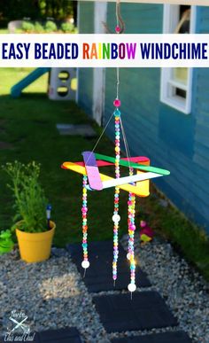 a colorful wind chime hanging from the side of a blue house with a potted plant next to it