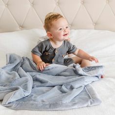 a little boy sitting on top of a bed under a blanket