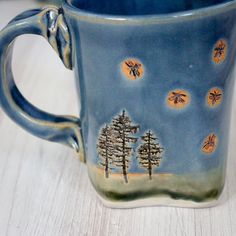 a blue mug with trees on it sitting on a table