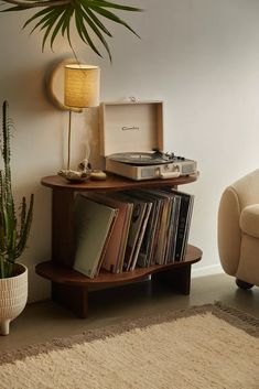 a record player sitting on top of a wooden shelf next to a potted plant