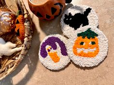 three decorated halloween coasters sitting on top of a table next to a pumpkin and jack - o'- lantern