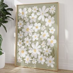 a white and yellow flower print on a green wall next to a potted plant