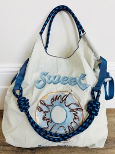 ♡ Introducing our adorable Blue Donut Embroidery Bag!  ♡ This bag features a cute donut design, expertly embroidered onto a durable and lightweight fabric.  ♡ The bag is perfect for carrying your everyday essentials, and can be carried in three different ways for your convenience. ♡ Whether you prefer to use it as a handbag, shoulder bag, or crossbody bag, this versatile accessory is perfect for any occasion. ♡ Our Ballet Rabbit Embroidery Bag is a fashionable and functional accessory that is sure to become a staple in your wardrobe. ♡    Medium (18x16in)       Removable Handle Included ♡ Order yours today! Cute Bags With Letter Embroidery For Everyday Use, Cute Letter Embroidery Bag, Cute Bag With Letter Embroidery, Donut Embroidery, Blue Harajuku Bag With Adjustable Strap, Rabbit Embroidery, Donut Design, Blue Donuts, Cute Donuts