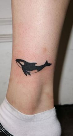 a small tattoo on the ankle of a woman with an orca whale in it