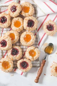 small cookies with jam on top are sitting on a cooling rack next to a spoon