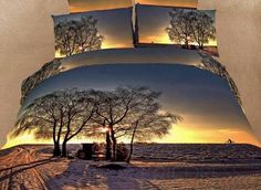 a bed covered in a comforter and pillows with trees on the snowy ground at sunset