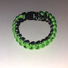 a green and black bracelet on a white table