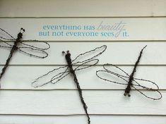 three metal dragonflies on the side of a house