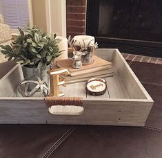 a tray with books, candles and other items on it in front of a fireplace