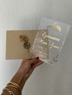 a woman holding up a wedding card with gold foil on the front and back side