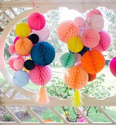 colorful honeycombs hanging from the ceiling in front of a gazebo with tassels