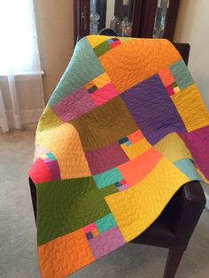 a multicolored quilt sitting on top of a wooden chair