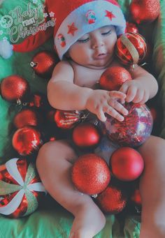 a baby is laying down surrounded by christmas ornaments