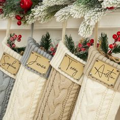 three christmas stockings hanging from a mantel with name tags on them and evergreen branches