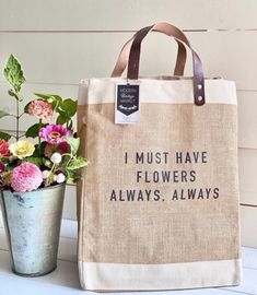 a bag with flowers in it sitting next to a potted plant