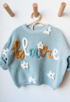 a blue sweater with flowers and the word love written in crochet on it