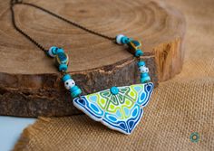 a blue and green necklace sitting on top of a piece of wood