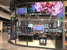 the inside of a jewelry store with flowers hanging from it's glass display case