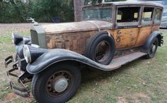 an old car is parked in the grass