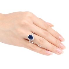 a woman's hand wearing a ring with a blue stone in the middle and two diamonds on each side