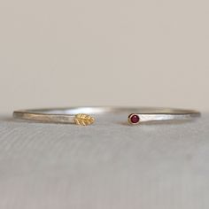 "Ruby or blue Sapphire 18k yellow gold and sterling silver \"Leaf and Flower Bud\" cuff. I set a 3mm gemstone in rich 18k gold and placed it opposite a handmade 18k gold leaf. The cuff is 2mm hammered sterling silver. This sweet cuff looks great worn alone or stacked with others. Choose from a selection of gemstones when you checkout. Comfortable and chic! Cuff - 5 1/2\"L with 3/4-1\" opening. Fits medium to small wrists and is slightly adjustable **Other sizes are available *This items is Made- Hand Forged Yellow Gold Cuff Bracelet Gift, Lake Oswego, Leaf Bracelet, Hammered Sterling Silver, Flower Bud, Silver Leaf, Birthstone Jewelry, Gold Leaf, Blue Sapphire