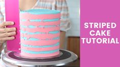 a woman holding a pink and blue striped cake on top of a metal platter