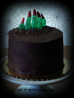 there is a chocolate cake with green candles on it and spider web in the background