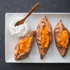 baked sweet potatoes with butter and yogurt are on a white plate next to a spoon