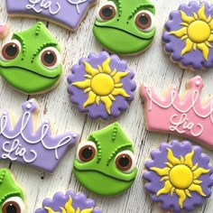 decorated cookies are arranged on a table with princess and frog faces in the middle one cookie has been cut out to look like they's smiling