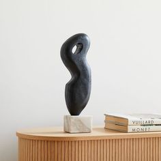 a black sculpture sitting on top of a wooden table next to two bookends