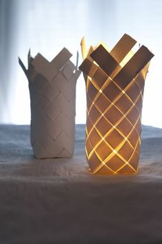 two paper vases sitting on top of a bed next to each other with lights in them