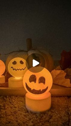 three lighted pumpkins sitting on top of a rug next to each other with faces drawn on them