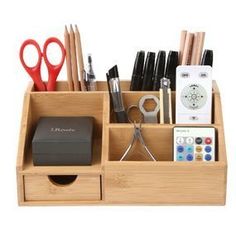 a wooden desk organizer with scissors, remotes and pens