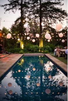 some paper lanterns are hanging over the pool